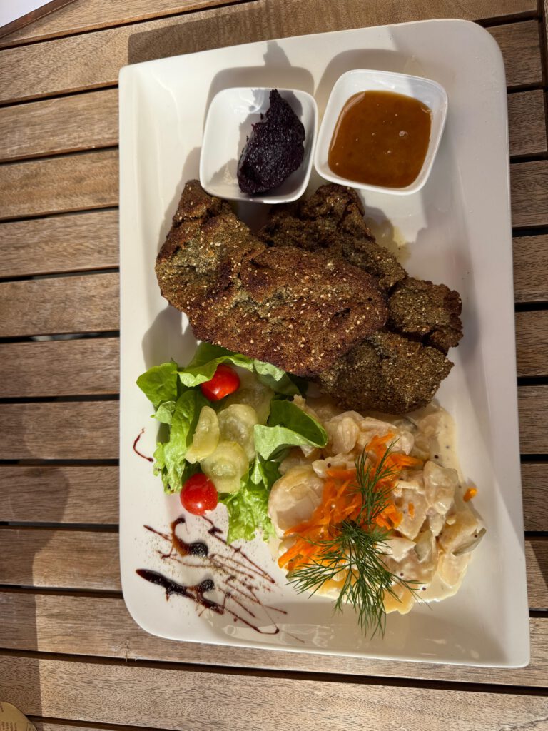 Kalbsschnitzel aus der Oberschale, sanft in Butter und Olivenöl gebraten mit glutenfreier Kürbiskern-Buchweizen Panade. Dazu hausgemachte Wildheidelbeermarmelade und cremiger Kartoffelsalat.
